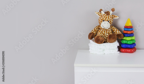 Children's stuffed toy giraffe and baby diapers on a gray background copi space photo