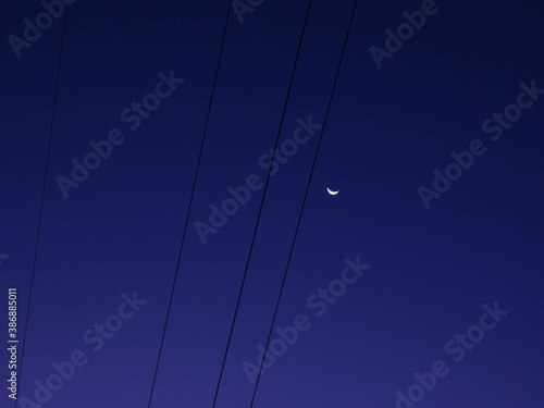 Moon and wires in the morning sky. Clear weather.