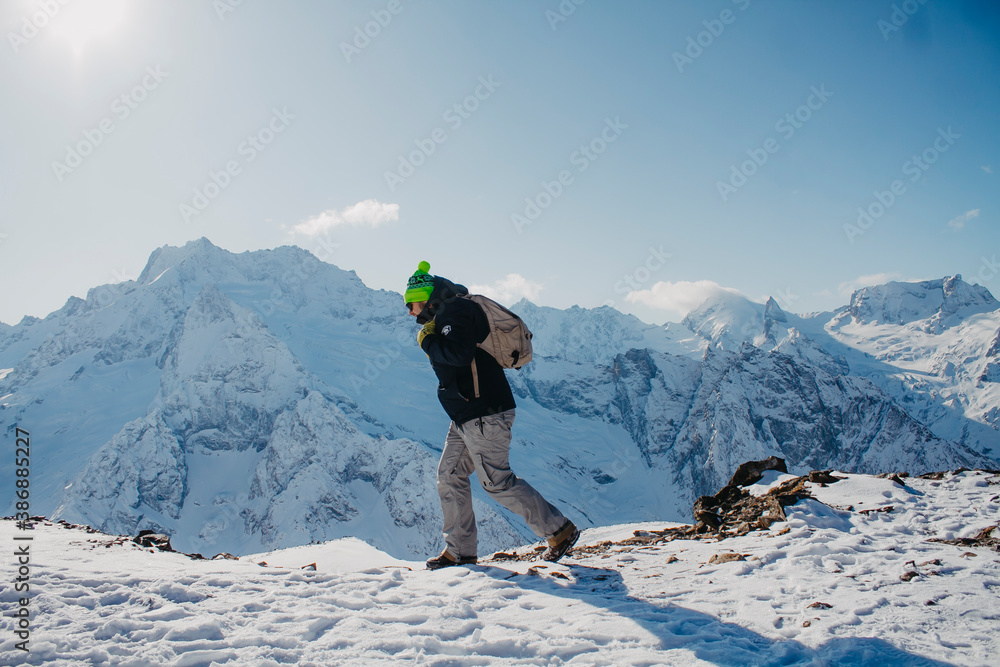 A man in winter clothes climbs the mountain. Excursion to the mountains. A man in winter clothes climbs the mountain. Excursion to the mountains.