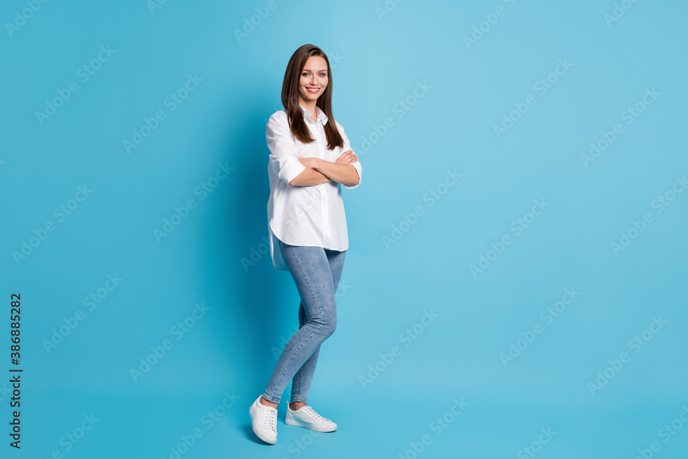 Full length photo of attractive lady arms crossed good mood wear white shirt jeans shoes isolated blue color background Full length photo of attractive lady arms crossed good mood wear white shirt jeans shoes isolated blue color background