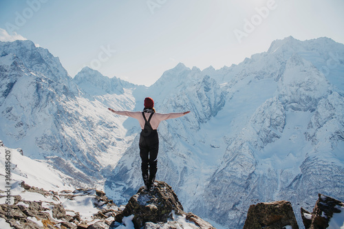 Winter holidays in the mountains. A young woman looks into the distance at the snowy mountains.