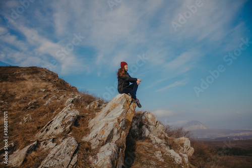 Traveler in the mountains on the background of blue sky in autumn. Sit on top.