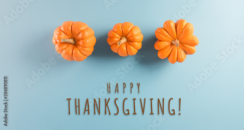 Thanksgiving background decoration from pumpkin on pastel blue background. Flat lay, top view with Thanksgiving text.