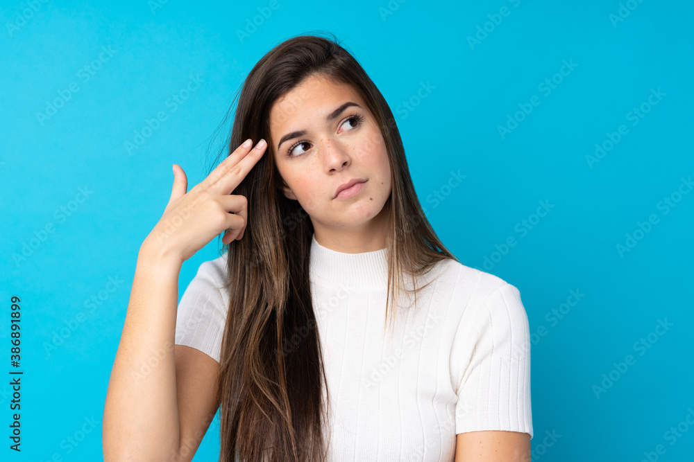 Teenager girl over isolated blue background with problems making suicide gesture Teenager girl over isolated blue background with problems making suicide gesture