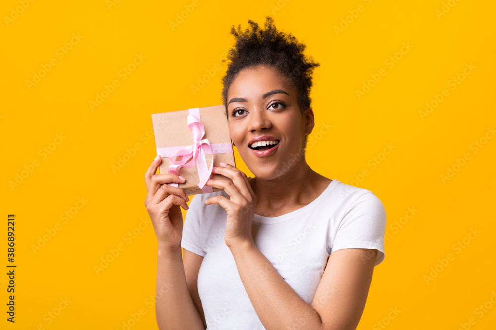 African American Woman Shaking Christmas Present At Studio African American Woman Shaking Christmas Present At Studio