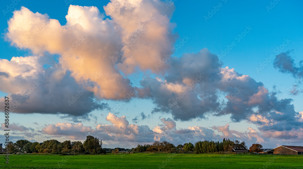 Due to the rising sun, the clouds above these farms along lake Zoetermeerse Plas are beautifully colored Due to the rising sun, the clouds above these farms along lake Zoetermeerse Plas are beautifully colored