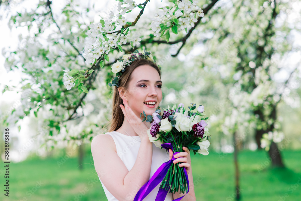 The bride in white wedding dress is holding a bouquet in green park. Summer wedding on sunny day. The bride in white wedding dress is holding a bouquet in green park. Summer wedding on sunny day.