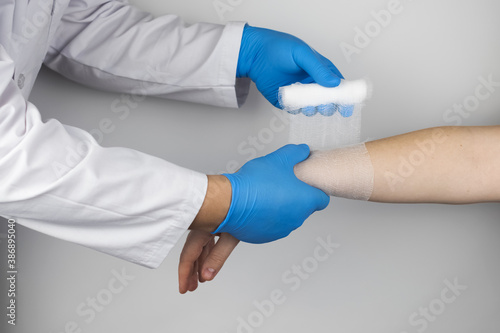 The traumatologist puts a bandage on the forearm of the female patient. The concept of help with fractures and sprains. The technique of applying a cruciform bandage.