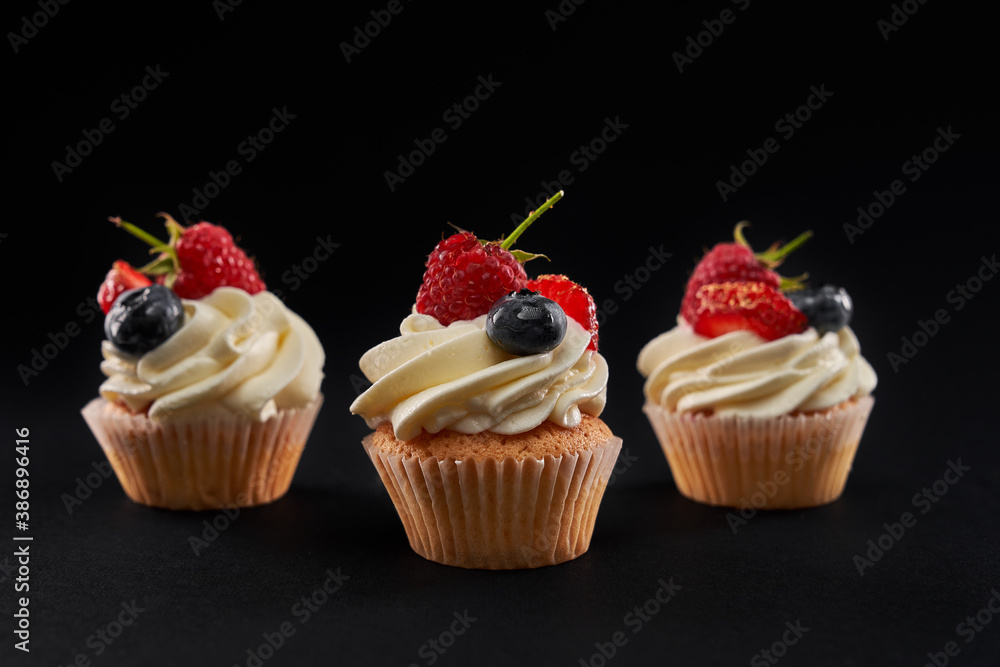Tasty mufins with berries, isolated on black background.