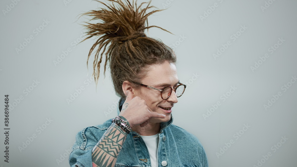Fototapeta premium Man in glasses imitating phone with hand. Smiling guy talking on imaginary phone