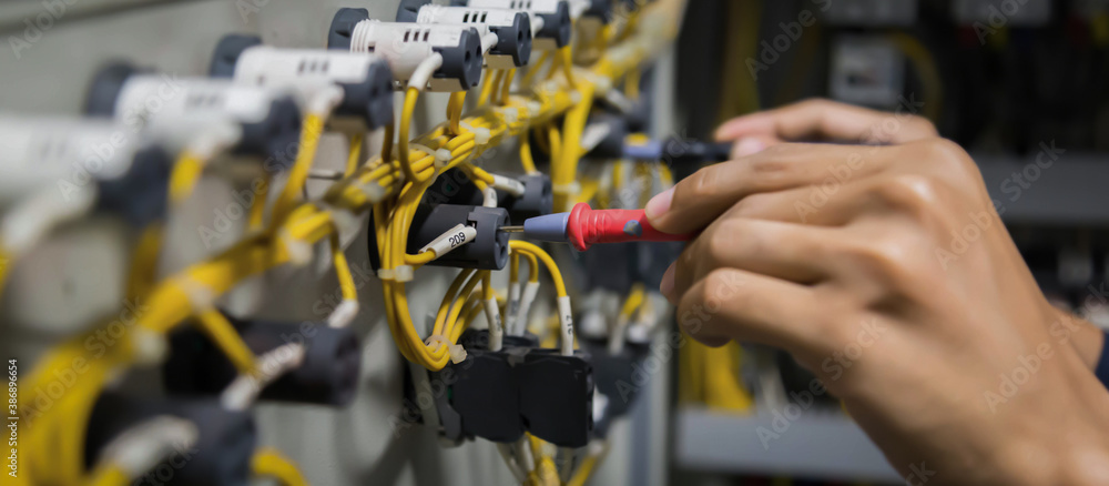 Obraz premium Electricians hands testing current electric in control panel.