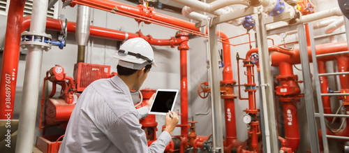 Bild auf Leinwand Engineer with tablet check red generator pump for water sprinkler piping and fire alarm control system