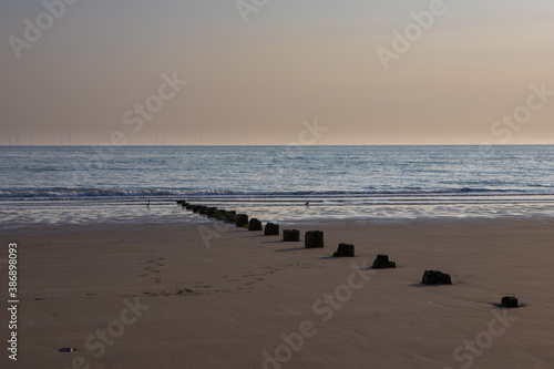 Wooden groynes on a golden sandy beach at sunset. Warm colours in the sky at Colwyn bay, North Wales