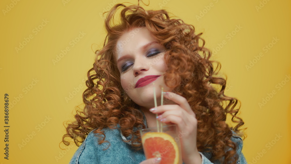 Joyful woman dancing with cocktail in hands. Redhead lady enjoying drink Joyful woman dancing with cocktail in hands. Redhead lady enjoying drink