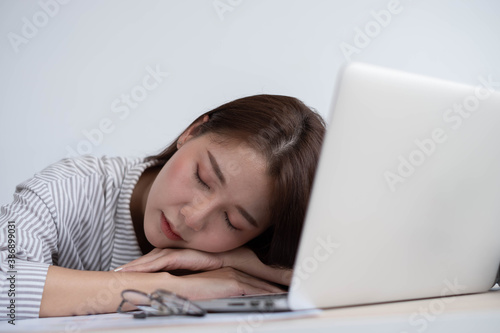 A female office worker in Asia fell asleep at the computer desk inside the office.