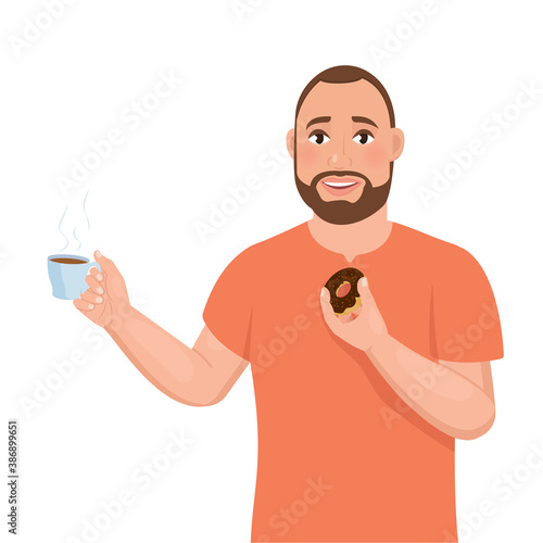 A young bearded guy holds a cup of coffee in one hand and a donut in the other.