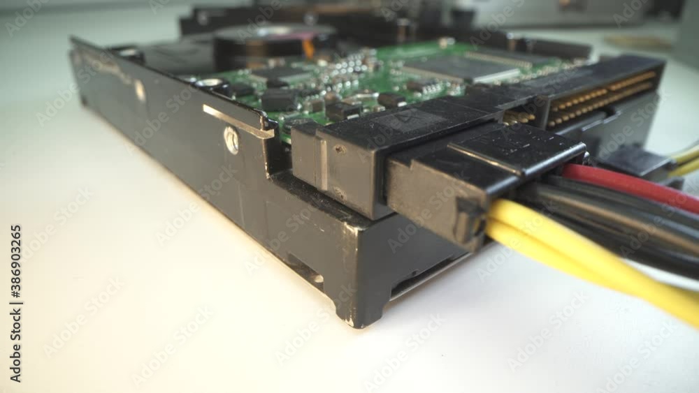 Old hard drive disk HDD with connected power cable in lab. White table. Macro shot with panorama. IDE connectors. Repair of household appliances concept. Old hard drive disk HDD with connected power cable in lab. White table. Macro shot with panorama. IDE connectors. Repair of household appliances concept.
