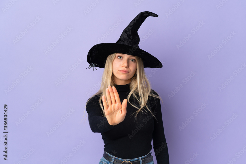 Young woman with witch costume over isolated background making stop gesture