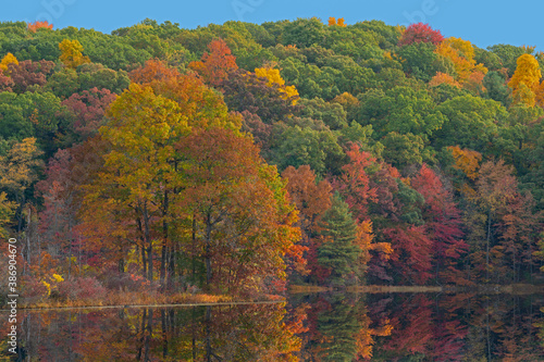 Autumn landscape of the shoreline of Hall Lake with mirrored reflections in calm water, Yankee Springs State Park, Michigan, USA