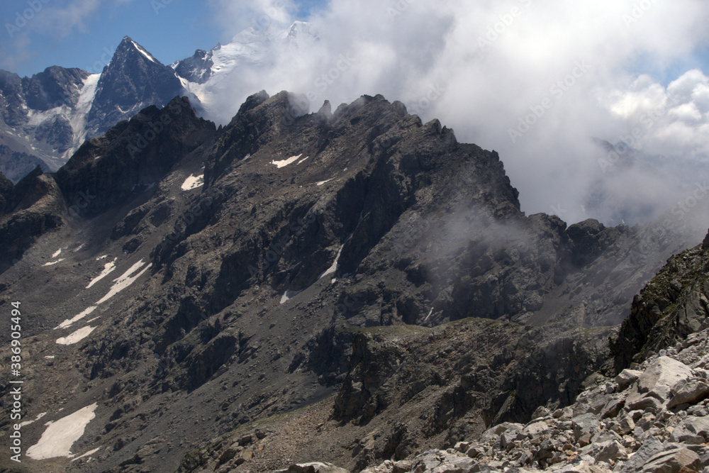 Mountain landscape with glaciers and clouds. View from the Koshtan mountain pass (3513 meters above sea level). Caucasus, Russia. Mountain landscape with glaciers and clouds. View from the Koshtan mountain pass (3513 meters above sea level). Caucasus, Russia.