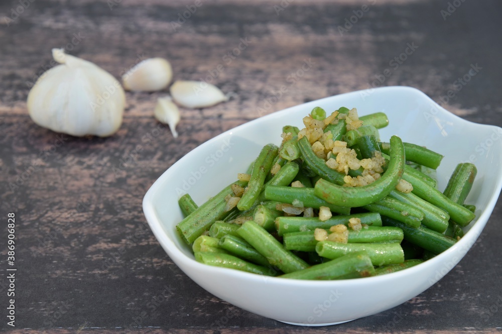 Sautéed green beans with garlic in a bowl on wooden background Sautéed green beans with garlic in a bowl on wooden background