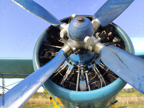Piston engine of an old biplane plane with a blue propeller close up © Александр Боев