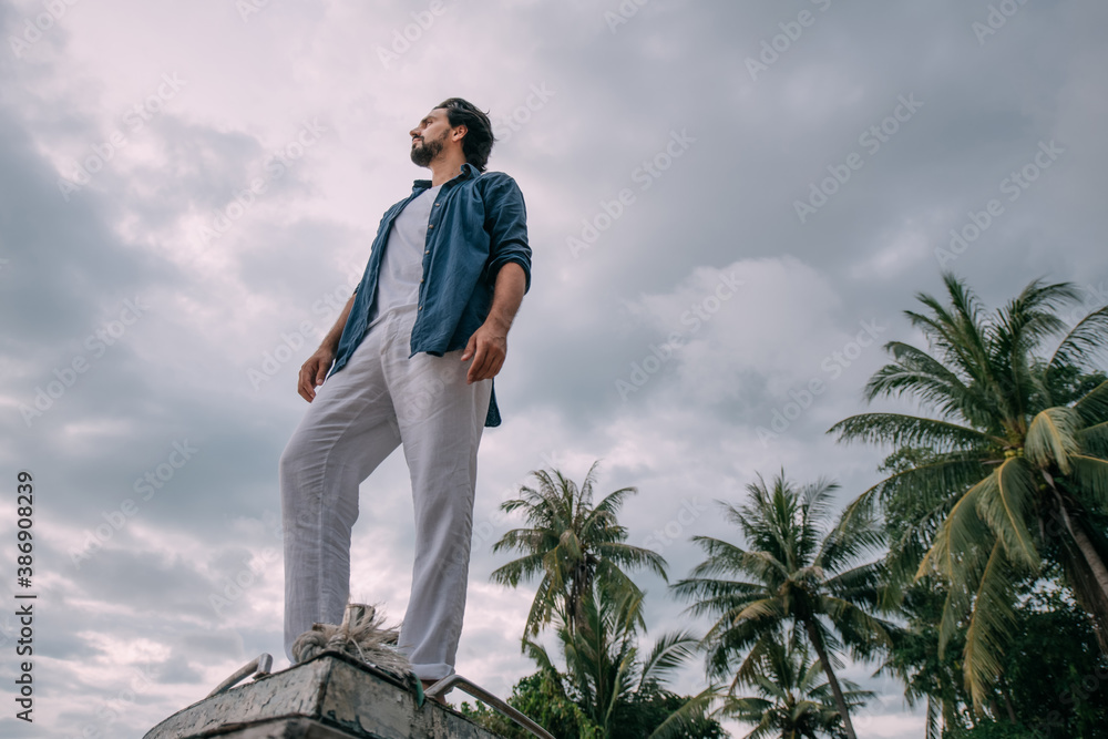 Lonely man on an old boat on a tropical island on a cloudy day Lonely man on an old boat on a tropical island on a cloudy day