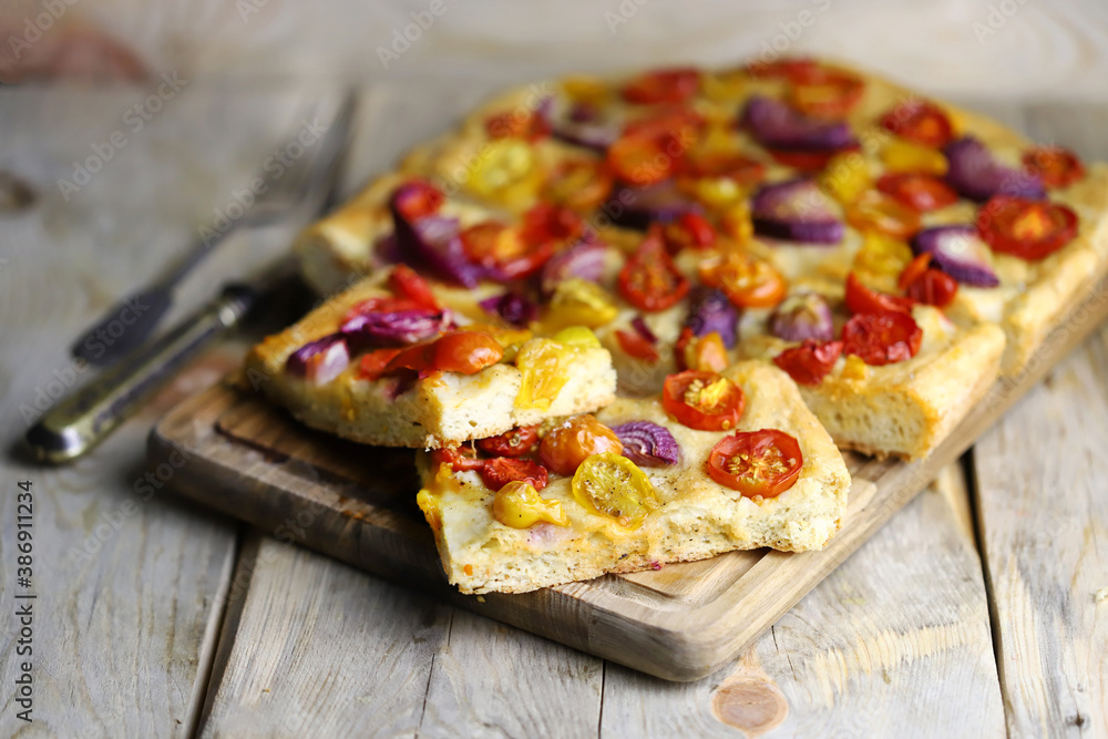 Selective focus. Homemade focaccia with cherry tomatoes and blue onions.