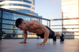 Young athletic man doing push ups outdoors.