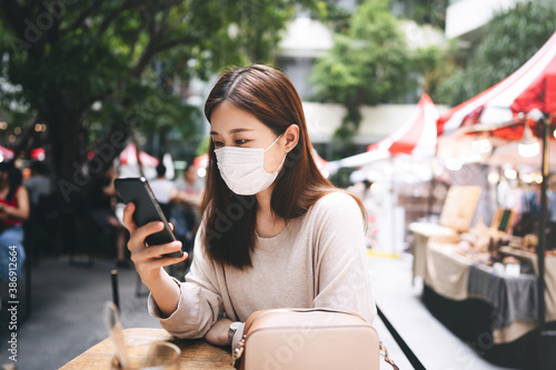 Photography Adult asian female with protective face mask for virus corona using mobile phone application