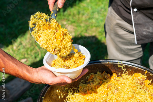 Photos Big cauldron with tasty pilaw just cooked outdoors on picnic on sunny day