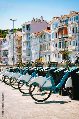 White and blue bicycles are in a row against the background of the beautiful houses.
