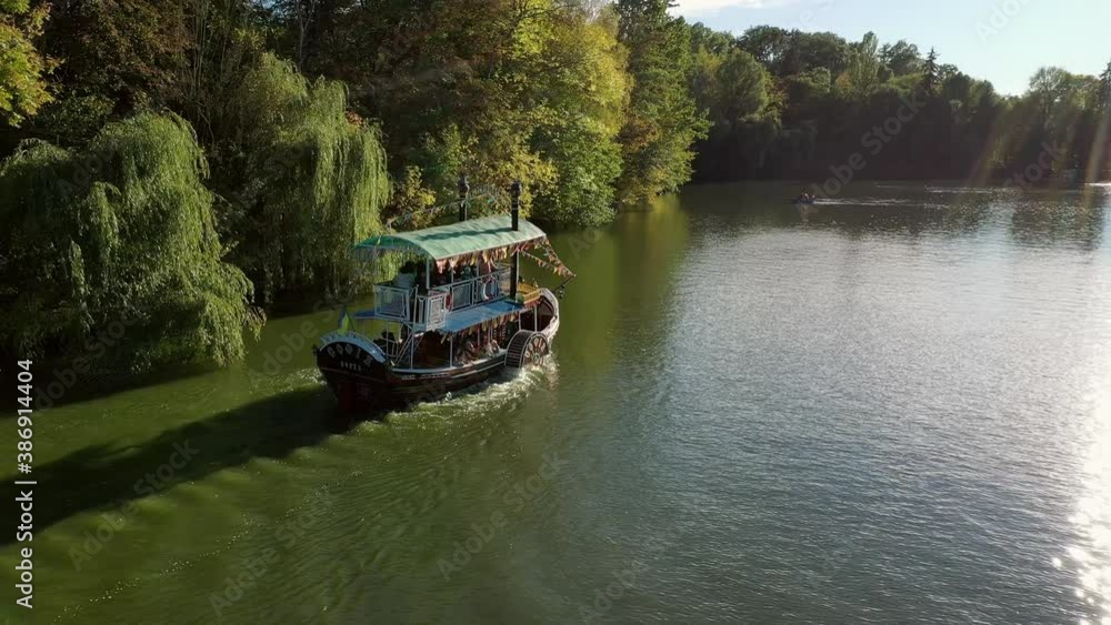 Autumn, a pleasure boat rolls tourists around the lake. Sofievsky Park, Uman, Ukraine. Port, blue. Autumn, a pleasure boat rolls tourists around the lake. Sofievsky Park, Uman, Ukraine. Port, blue.