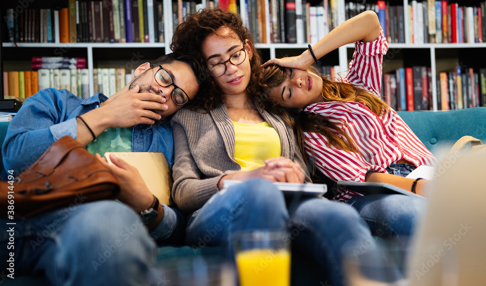 Obraz premium College, study, university and education concept. Group of tired students learning in library