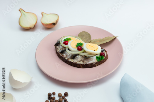 Spice Baltic sea sprats sandwich with onion and egg slices. Traditional Estonian cuisine.