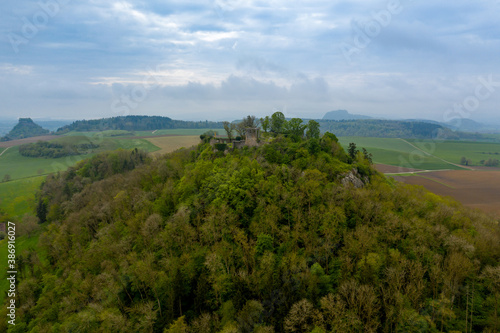 Aerial view of a forested hill with a castle ruin on top of it