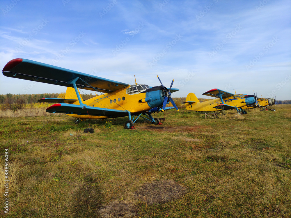 Parking yellow old piston aircraft biplanes with a propeller in the summer on the tarmac in Sunny weather Parking yellow old piston aircraft biplanes with a propeller in the summer on the tarmac in Sunny weather