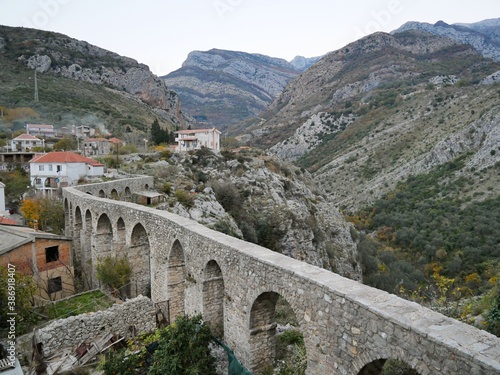 Winding old viaduct set against striped mountains and houses with tiled roofs