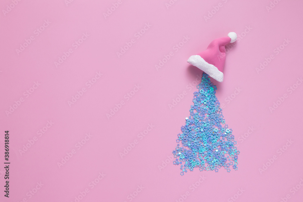 new year holidays concept creative sparkling christmas tree on colored background wearing santa claus hat, top view with copy space new year holidays concept creative sparkling christmas tree on colored background wearing santa claus hat, top view with copy space