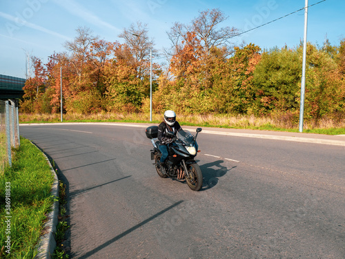 Motorcyclist in motion. Woman biker on a black motorcycle in traffic on a rural autumn road