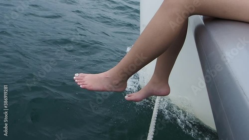 Closeup of the woman legs sitting on a cruising yacht.