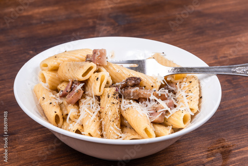 Pasta alla gricha with pancetta in a plate on a dark wooden table close up, top view photo