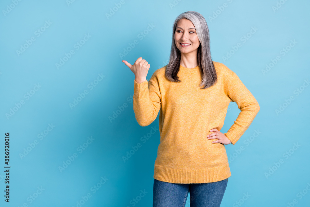 Sale for pensioners only. Photo of attractive lovely old lady white grey hairstyle hand hips direct finger empty space wear yellow jumper jeans isolated blue pastel color background Sale for pensioners only. Photo of attractive lovely old lady white grey hairstyle hand hips direct finger empty space wear yellow jumper jeans isolated blue pastel color background