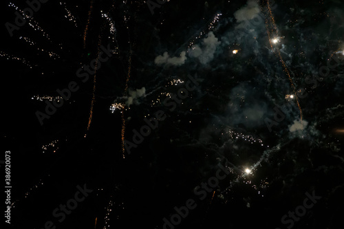Golden rare stripes of fireworks with smoke and bokeh on a black background.