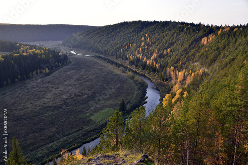 A bend of the Irgina River in a deep river valley among a bright autumn forest. In the foothills of the Western Urals, golden autumn.