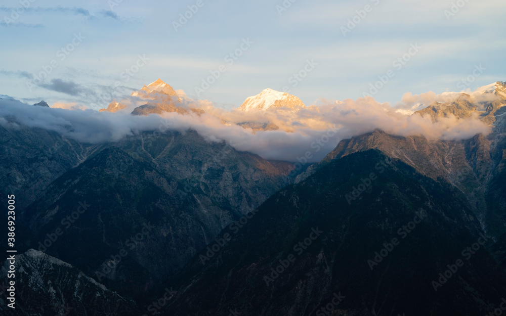 Snow peaked Himalayas shrouded in clouds and mountain slopes. Kalpa, India.