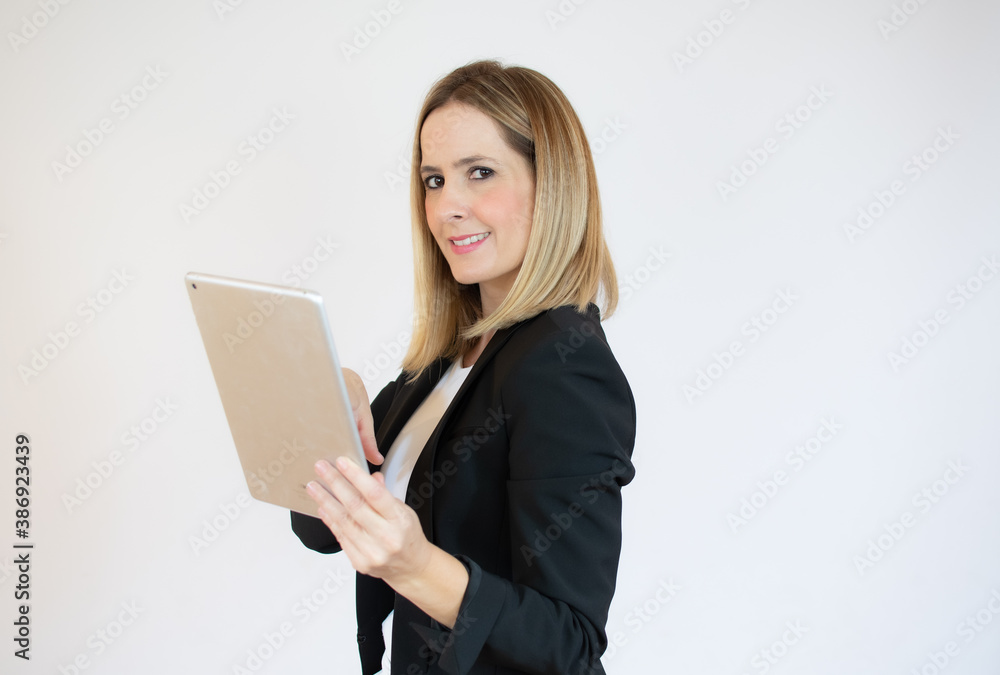 Joyful profile businesswoman holding a tablet in her hands and smiling Joyful profile businesswoman holding a tablet in her hands and smiling
