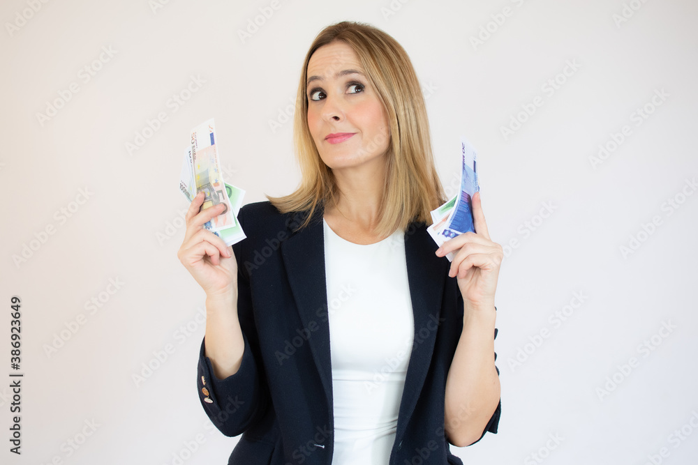 Young friendly businesswoman holding money in her hands and looking to the side with an embarrassed face on isolated white background. Concept of wealth, win, credit. Copy space Young friendly businesswoman holding money in her hands and looking to the side with an embarrassed face on isolated white background. Concept of wealth, win, credit. Copy space