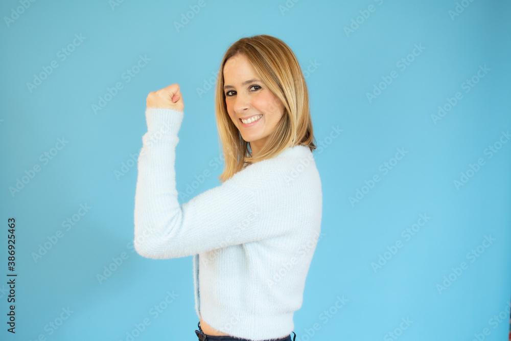 Beautiful young woman happy and excited expressing winning gesture. Successful pretty woman celebrating victory, triumphant, studio shot over blue background Beautiful young woman happy and excited expressing winning gesture. Successful pretty woman celebrating victory, triumphant, studio shot over blue background