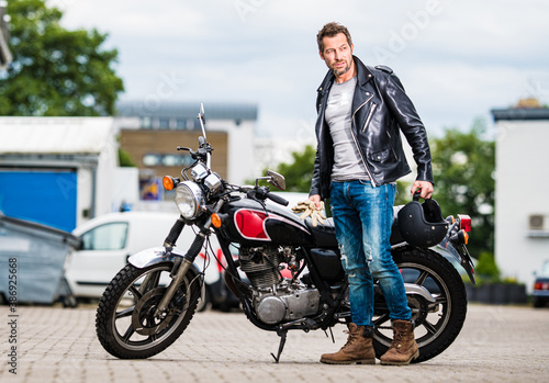 Fotografia Mann in Lederjacke sitzt cool auf einem Cofferacer Motorrad mit einem Zylinder